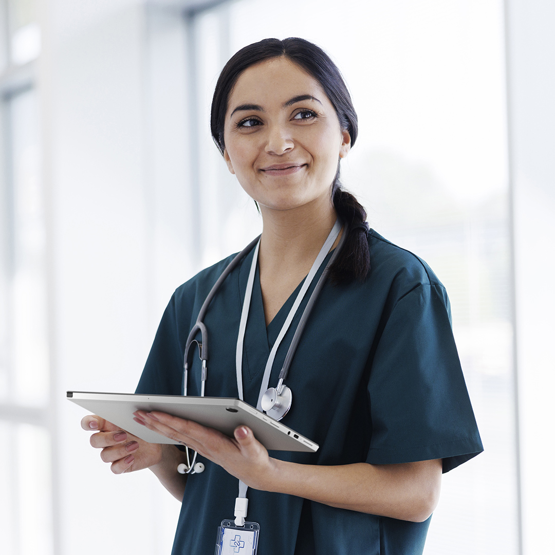 A female doctor is holding a detachable asus chromebook, looking at somewhere, with a smile on her face